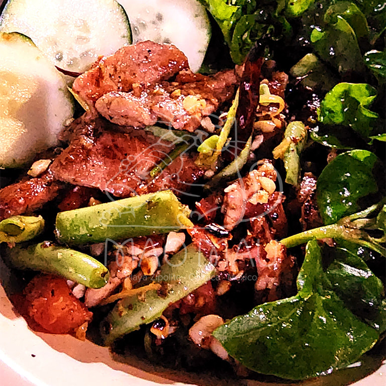 Tum Kor Moo**+ - marinated grilled pork (180g) with tomato, string beans, lime, chilies & peanuts